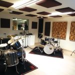 Sala prova con trattamento acustico: pannelli fonoassorbenti sospesi a soffitto, pannelli a parete e diffusori in legno