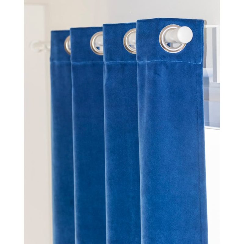 Tendone in velluto blu con occhielli a vela metallici infilati su un bastone da tenda bianco