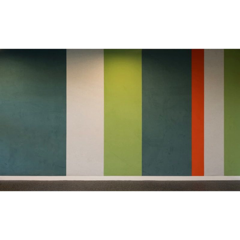 Parete rivestita con fasce verticali di tessuto fonoassorbente Autex Vertiface nei toni verde, avorio, petrolio e arancio